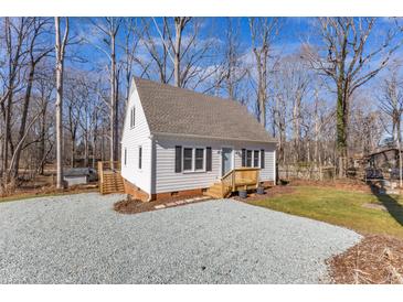 Charming white home featuring a gravel driveway and a well-maintained yard with a natural wooded backdrop at 612 Miller Rd, Hillsborough, NC 27278
