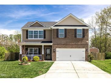 Charming two-story home featuring a well-manicured lawn, two-car garage, and a welcoming front porch at 1000 Milkweed Ct, Zebulon, NC 27597