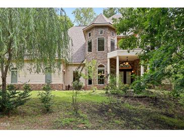 Charming stone and siding home featuring a turret, covered entrance, and lush landscaping at 1217 Mauldin Rd, Wake Forest, NC 27587