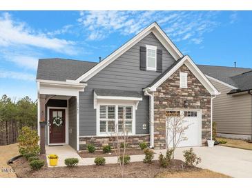 Charming two-story home featuring gray siding, stone accents, a quaint front porch, and an attached garage at 1243 White Flint Cir, Durham, NC 27703
