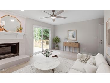 Bright living room featuring a brick fireplace, ceiling fan, and sliding glass doors to the deck at 206 Woods Run, Knightdale, NC 27545