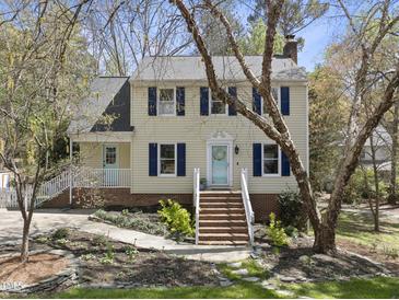 Charming two-story home with blue shutters, a quaint front door, and a landscaped yard with mature trees at 323 Brandermill Dr, Durham, NC 27713