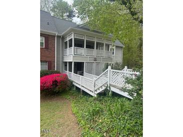 Exterior view of condo with latticework balcony, white picket fence, and lush landscaping at 411 Gooseneck Drive # B6, Cary, NC 27513