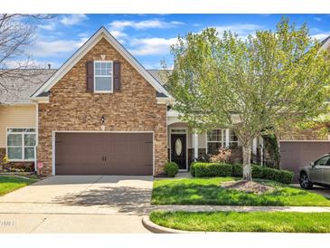 Charming townhome with stone accents, a brown garage door, manicured lawn and inviting curb appeal at 5033 Homeplace Dr, Apex, NC 27539