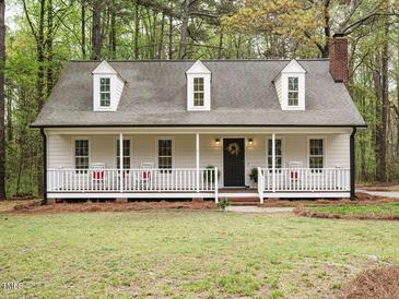 Charming home with inviting front porch, rocking chairs, and well-maintained yard in a wooded setting at 5209 Rivington Rd, Fuquay Varina, NC 27526