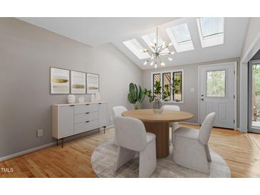 Bright dining room features skylights, modern chandelier, wood floors, and neutral decor for elegant, comfortable dining at 58 Stoneridge Rd, Durham, NC 27705