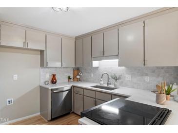 Updated kitchen featuring white countertops, tiled backsplash, stainless steel appliances, and gray cabinets at 58 Stoneridge Rd, Durham, NC 27705