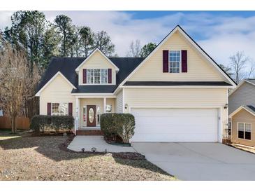 Charming yellow home featuring well-maintained landscaping, a two-car garage and a welcoming entryway at 605 Lakeview Ave, Wake Forest, NC 27587