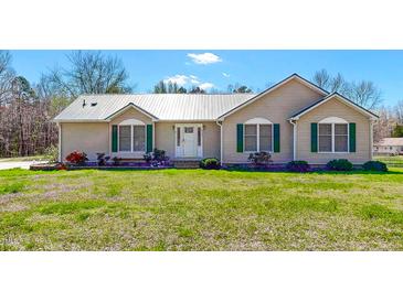 Charming single-story home with metal roof, complemented by a lush green lawn and manicured garden at 772 Old Allensville, Roxboro, NC 27574