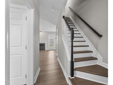 Inviting entryway features hardwood floors and a staircase with black handrail leading to upper level at 8700 Leeds Forest Ln, Raleigh, NC 27615