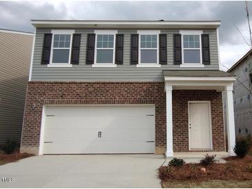 Charming two-story home with a brick facade, attached garage, and inviting front entrance at 1165 Solace Way, Rolesville, NC 27571