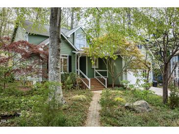 Charming green home with brick pathway, lush landscaping, and inviting front porch at 1550 Pathway Dr, Carrboro, NC 27510