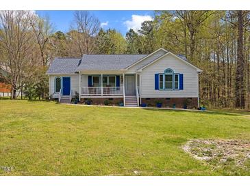 Charming white house with blue accents, a welcoming front porch, and a lush green lawn at 163 Ridge Way Ln, Clayton, NC 27520