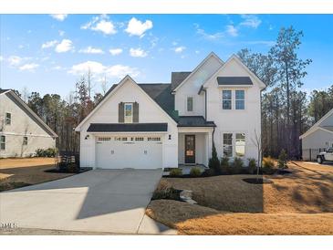 Charming two-story home featuring a pristine white facade, a two-car garage, and a neatly landscaped front yard at 201 W Amber Oak Drive, Selma, NC 27576