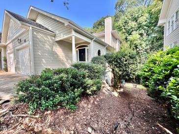 Charming home exterior featuring lush landscaping, arched front door, and attached garage at 212 Columbia W Pl, Chapel Hill, NC 27516