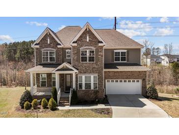 Charming two-story home boasts a stone and brick facade, attached two car garage, and a well-manicured front yard at 2713 Tunstall Grove Dr, Apex, NC 27523
