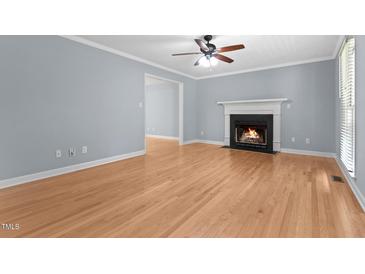 Bright living room with hardwood floors, fireplace and ceiling fan at 302 Rushingwater Dr, Cary, NC 27513