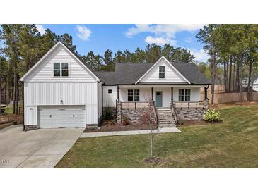 Charming two-story home boasts a light blue front door, covered porch and a manicured lawn at 381 Heart Pine Dr, Wendell, NC 27591