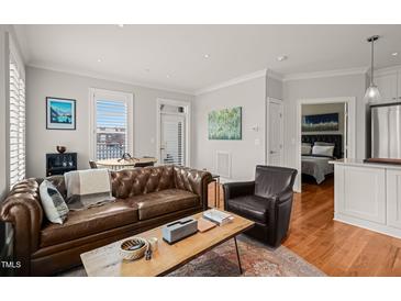 Inviting living room with a comfortable leather couch and access to a bedroom and outdoor dining space at 605 Smedes Pl # A, Raleigh, NC 27605