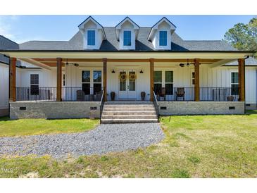 Beautiful modern farmhouse with a welcoming porch, gray roof, black railings, and lovely landscaping at 6480 Beaver Creek Rd, New Hill, NC 27562