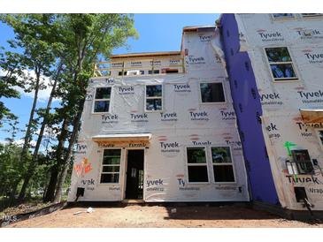 Unfinished exterior of a new construction home, wrapped in Tyvek HomeWrap, with windows installed and the framing exposed at 6960 Doddridge Ln # 15, Cary, NC 27519