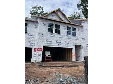 Unfinished townhome exterior featuring the front entrance and a two-car garage under construction at 6962 Doddridge Ln # 14, Cary, NC 27519