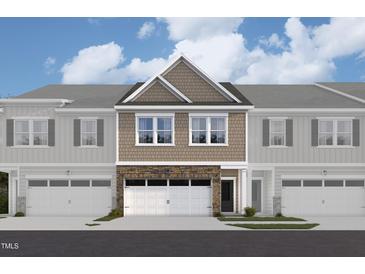 New construction townhome featuring neutral siding, stone accents and two-car garage at 6962 Doddridge Ln # 14, Cary, NC 27519