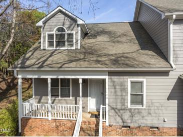 Charming two-story home featuring a covered porch with white railings and gray siding, plus red brick stairs and facade at 1426 Quarter Pt, Raleigh, NC 27615