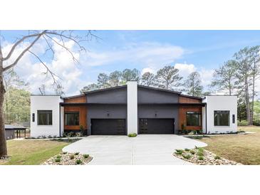 Modern duplex featuring a gray and white exterior, black garage doors, and a concrete driveway and walkway at 1625 Bruce Circle, Raleigh, NC 27604