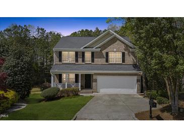 Charming two-story brick home with a well-manicured lawn, attached garage, and inviting front porch at 219 Arbordale Ct, Cary, NC 27518