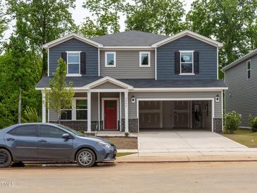 Two-story home with a two-car garage, red door, and gray and blue siding at 2202 Cherry Creek Rd, Haw River, NC 27258