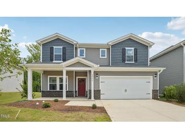 Charming two-story home featuring a two-car garage, red door, and a cozy front porch at 2202 Cherry Creek Rd, Haw River, NC 27258