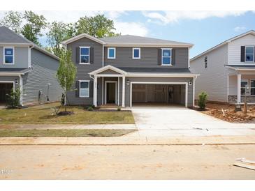 Two-story home featuring gray siding, a covered entryway, attached garage, and freshly installed lawn at 2210 Cherry Creek Rd, Haw River, NC 27258