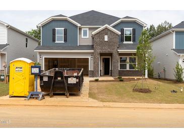 New two-story home featuring mixed siding, brick accents, an open garage and unfinished landscaping, ready for personalization at 2211 Cherry Creek Rd, Haw River, NC 27258
