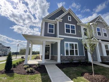 Charming two-story home with blue siding, stone accents, and a welcoming covered front porch at 2401 Whitewing Ln, Wendell, NC 27591