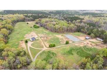 Scenic aerial view of horse property featuring a house, fields, pond, and outbuildings at 3880 L Lawrence Trl, Graham, NC 27253