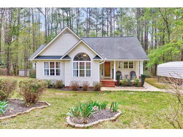 Charming single-story home with a well-manicured lawn, inviting front porch, and appealing architectural details at 413 Correy Pl, Clayton, NC 27520
