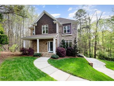 Charming two-story home featuring a stone and brick facade, complemented by a lush, landscaped front yard at 8418 Wheatstone Ln, Raleigh, NC 27613