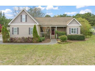 Charming single-story home with a well-manicured lawn and inviting front porch with a red door at 8437 Little Woody Ct, Zebulon, NC 27597