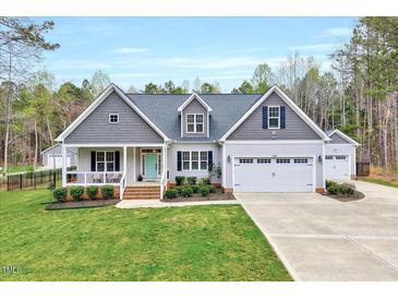 Charming home featuring gray siding, a well-manicured lawn, and a welcoming front porch at 1165 Shonele Ln, Stem, NC 27581
