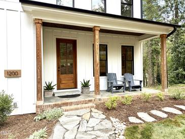 Charming front porch with wooden pillars, modern seating, and inviting stone pathway, offering a cozy welcome at 1200 Roosevelt Dr, Chapel Hill, NC 27514