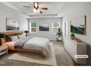 This bedroom features a tray ceiling, neutral walls, windows, and ceiling fan, providing a serene retreat at 1206 Kafka Dr, Fuquay Varina, NC 27526