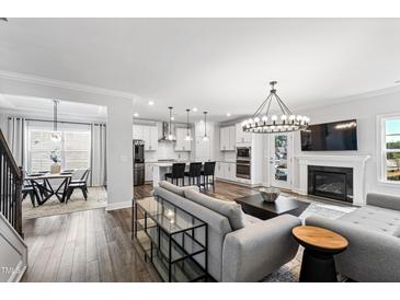 Bright open-concept living space with modern lighting, fireplace, and adjacent dining area with hardwood floors at 139 Pronghorn Deer Ct, Garner, NC 27529