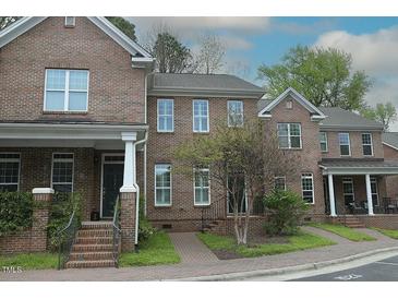 Brick townhome featuring a manicured lawn, gray roof, and brick steps leading up to the front door at 1523 Yarborough Park Drive, Raleigh, NC 27604