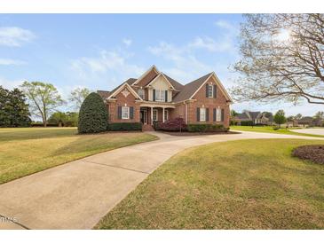Charming brick two-story home with lush front lawn, mature trees, and a winding concrete driveway at 21 W Paige Wynd Dr, Angier, NC 27501