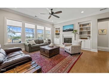 Bright living room featuring a fireplace, built-in shelves, and expansive windows offering scenic views at 216 Ocean Jasper Dr, Holly Springs, NC 27540