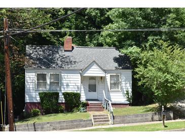 Charming cottage-style home with white siding, brick foundation, and well-maintained landscaping at 301 Dunstan Ave, Durham, NC 27707