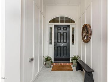 Inviting black front door with glass accents and potted plants offers curb appeal and welcoming entry at 9 Hayden Pond Ln, Chapel Hill, NC 27517