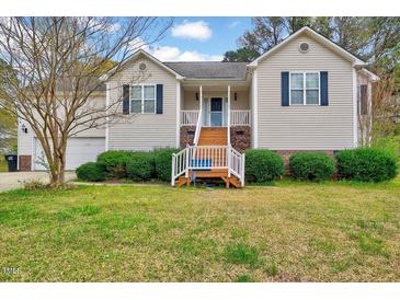 Charming home featuring a well-manicured lawn, complemented by a welcoming front porch and two-car garage at 91 Buckingham Ct, Smithfield, NC 27577