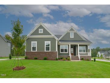 Charming single-story home with a brick foundation, green siding, a covered porch, and a well-manicured lawn at Lot 2 Northpointe Farms Trl, Efland, NC 27243